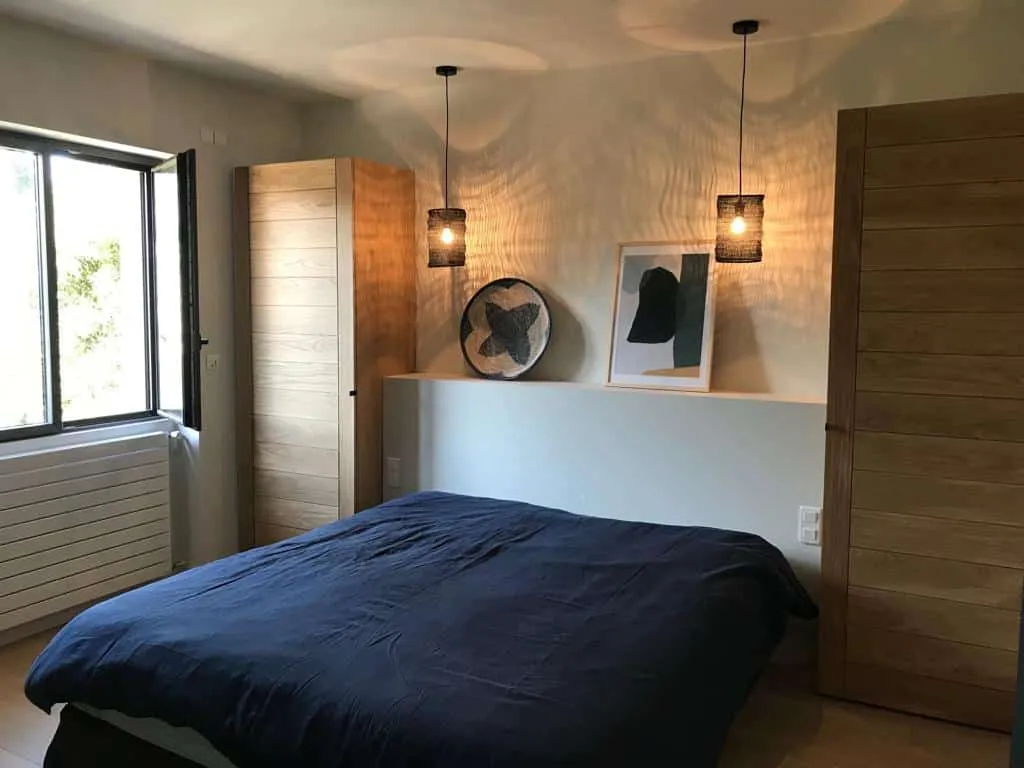 Chambre avec lit au linge bleu marine et deux armoires en chêne sur mesure